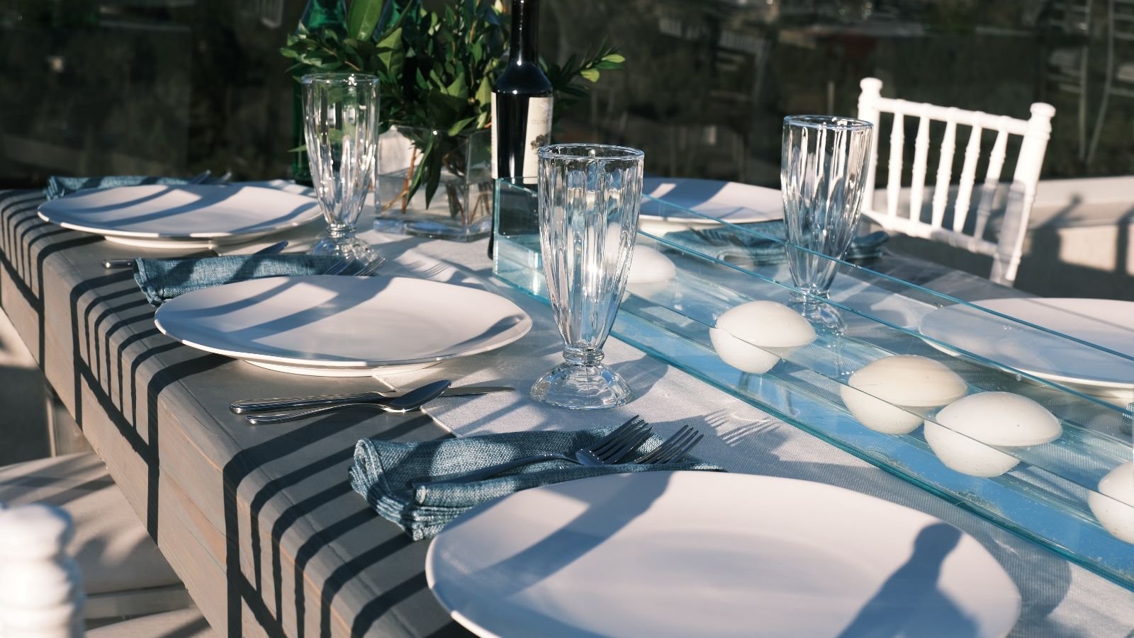Table set with white plates, glasses and a striped runner at a Bora event